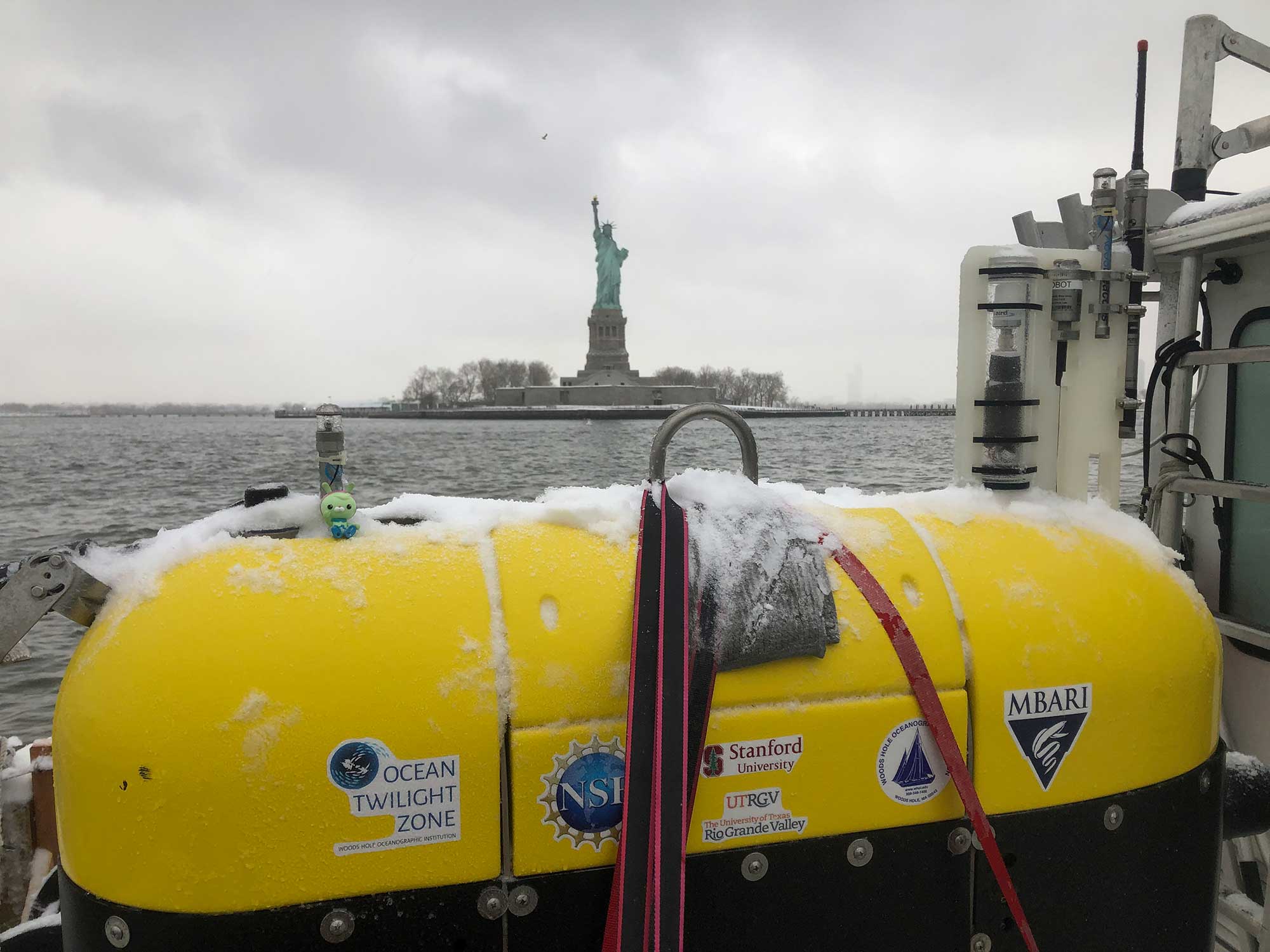 The R/V <em>Catapult</em> passes the Statue of Liberty on its way to Elizabeth, New Jersey, with the snow-covered <em>Mesobot</em> stowed safely on its deck. Once the vehicles reach their destination, they'll be hoisted aboard a larger shipping vessel and carried to Bermuda.