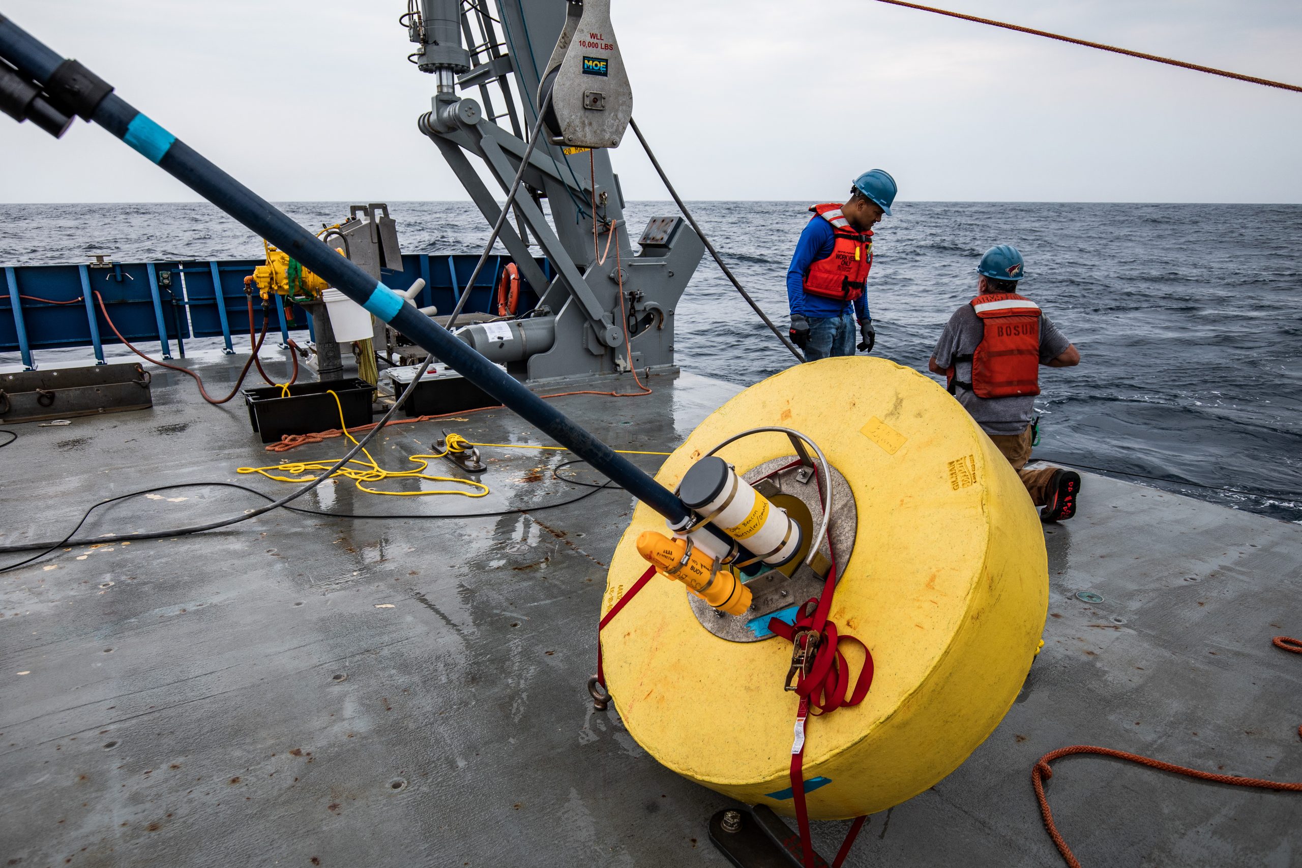 WHOI postdoctoral scholar Wokil Bam (Café Thorium Lab) and Bosun Pete Lariarkos begin to unstrap a surface float that will mark the location of sediment traps being deployed amid the ocean twilight zone.