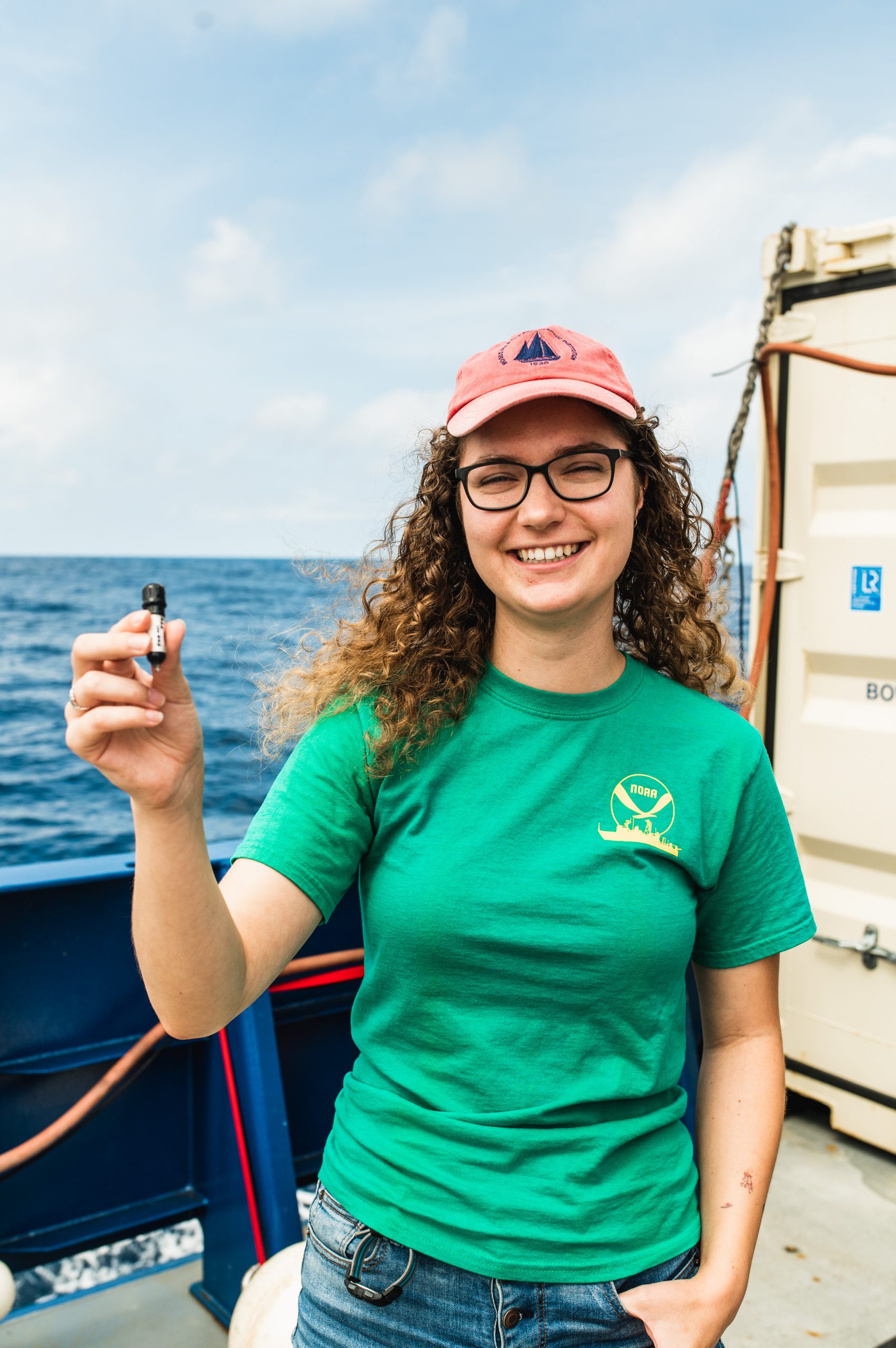 MIT-WHOI Joint Ciara Willis (Fish Ecology Research Lab) poses with the new ROAM tag with which she and advisor Simon Thorrold plan to use to track apex predators in the ocean twilight zone. Using four sound source moorings, these small receivers can process their precise location in the water column, without the animal having to breach the surface waters.