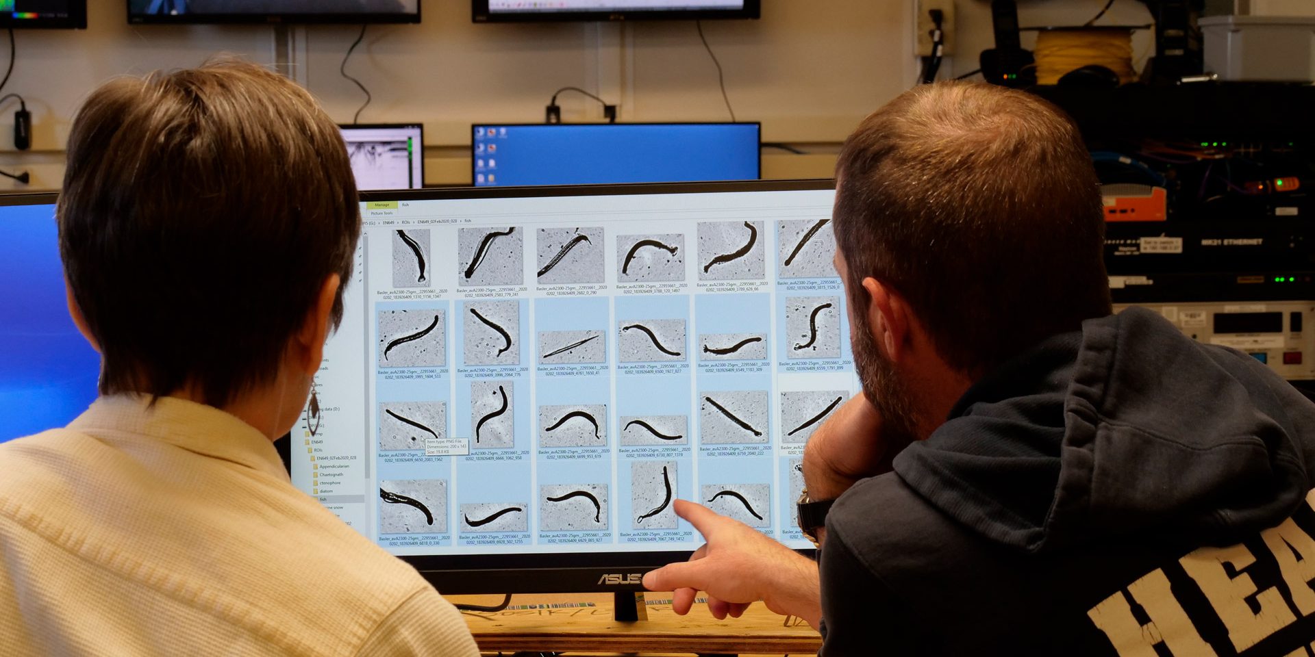 two scientists look at a computer screen with what appears to be a repeating image