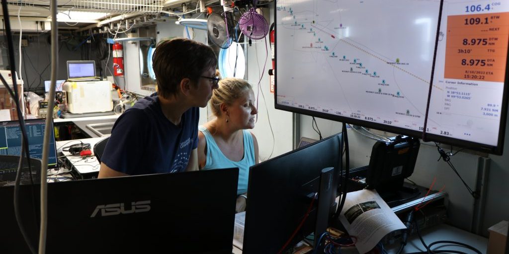 OTZ project lead Heidi Sosik and WHOI senior research assistant Taylor Crockford review data coming in from the towed sled Stingray, which holds multiple sensors and an advanced shadowgraph camera to collect images of gelatinous animals at depth. The monitor above them displays sampling stations and the position of various vehicles, ships, and instruments that are in the water at any given time. (Photo © Woods Hole Oceanographic Institution)