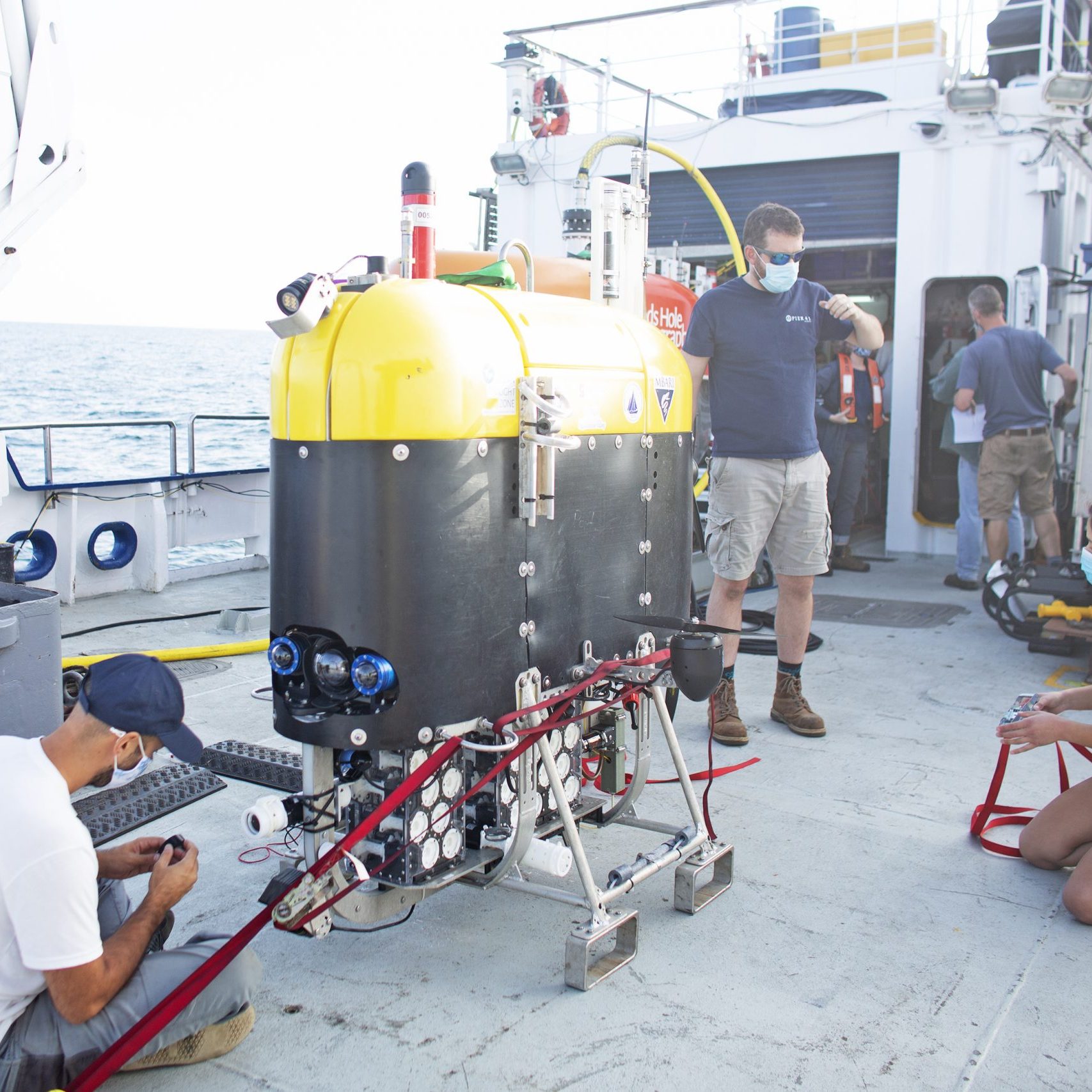 The Mesobot team begins the pre-dive routine, removing safety straps and checking equipment, on the aft deck of E/V Nautilus. (Photo: OET/Nautilus Live)
